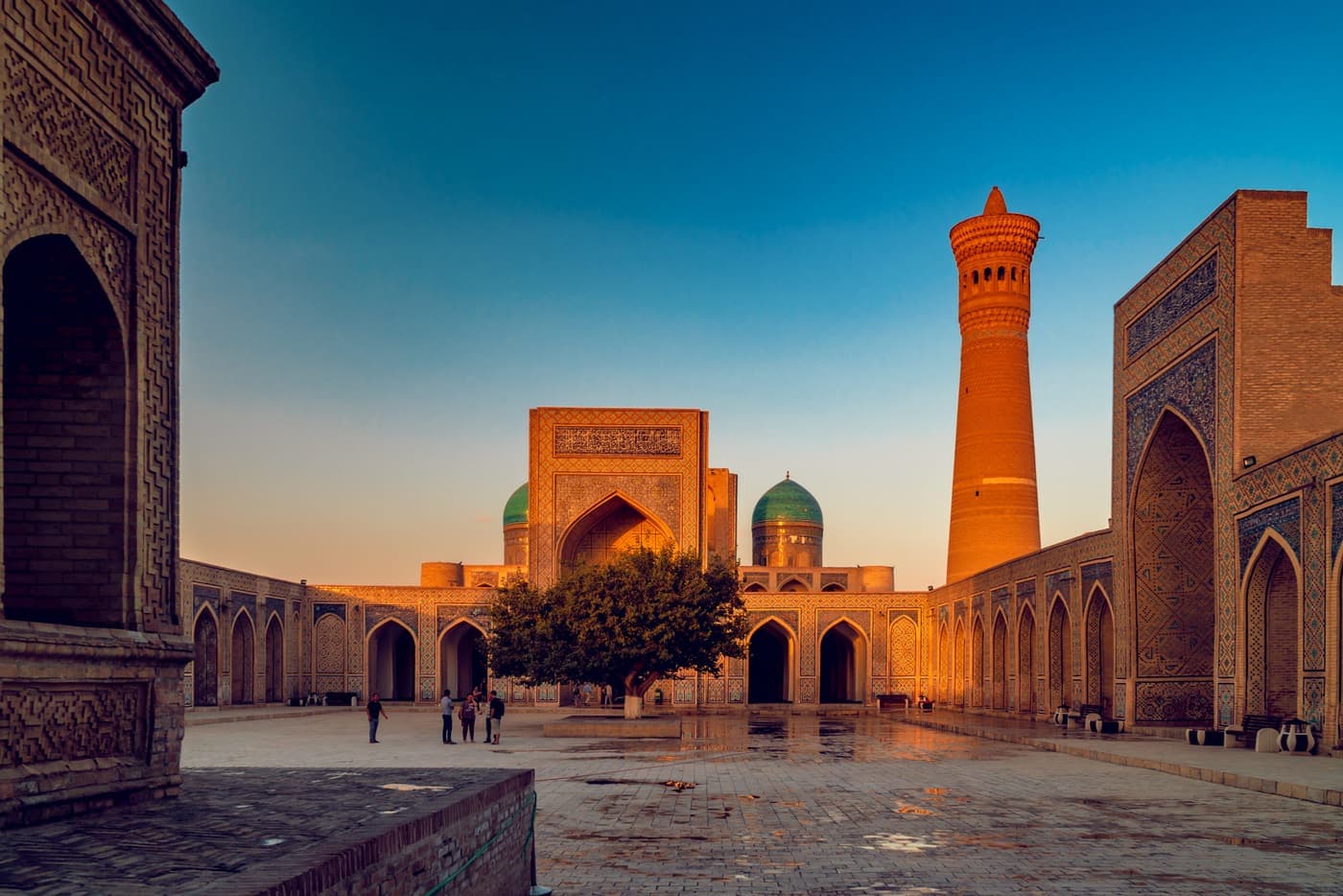 The Kalyan Mosque courtyard at sunset, with the minaret and the domes of Mir-i-Arab beyond