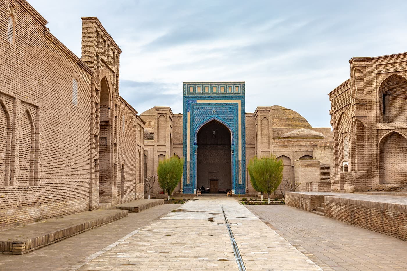 The long courtyard of Sultan Saodat between rows of brick mausoleums, ending at a blue-tiled portal