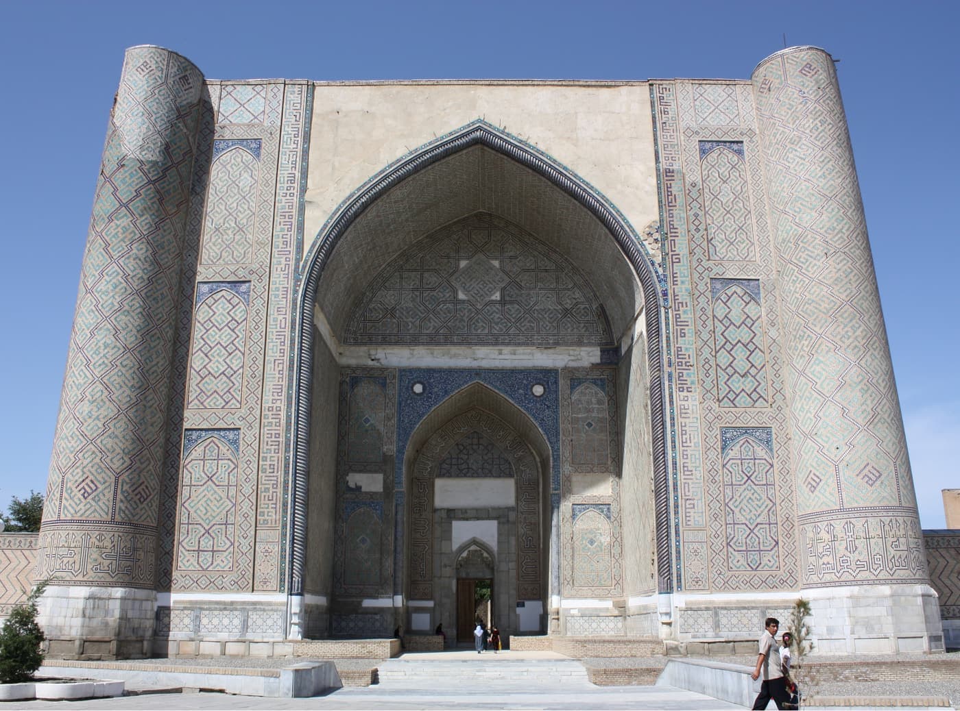 The huge arched portal of the Bibi-Khanym Mosque, with visitors small at its foot