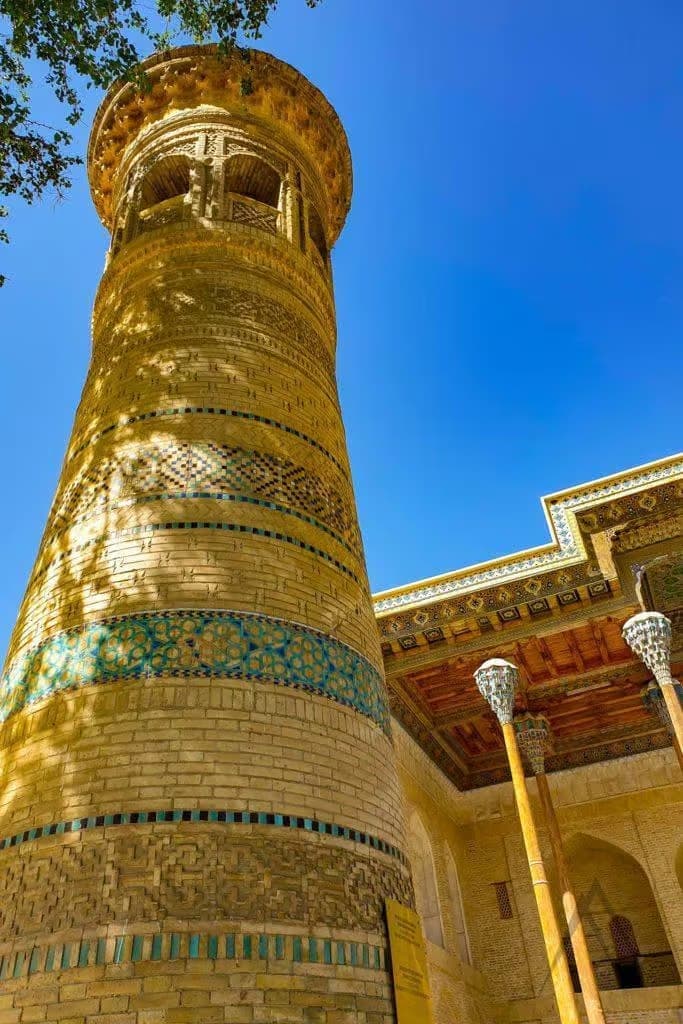 Looking up the minaret with the carved eaves of the mosque alongside