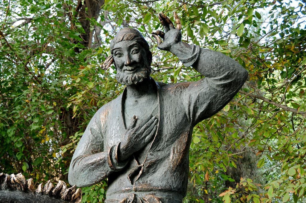 Close view of Nasreddin's face and raised hand