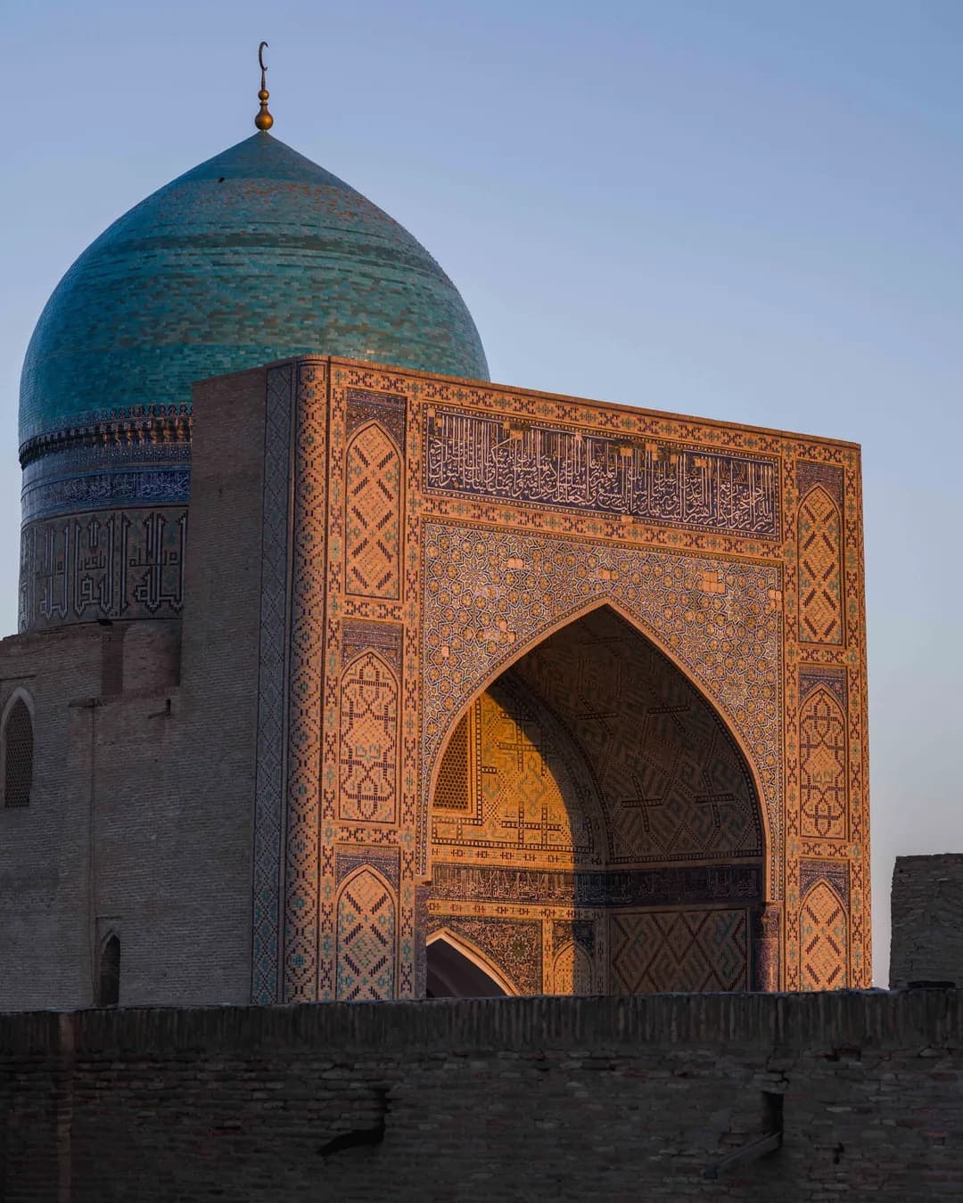 The turquoise dome and tiled portal of the Kalyan Mosque in evening light
