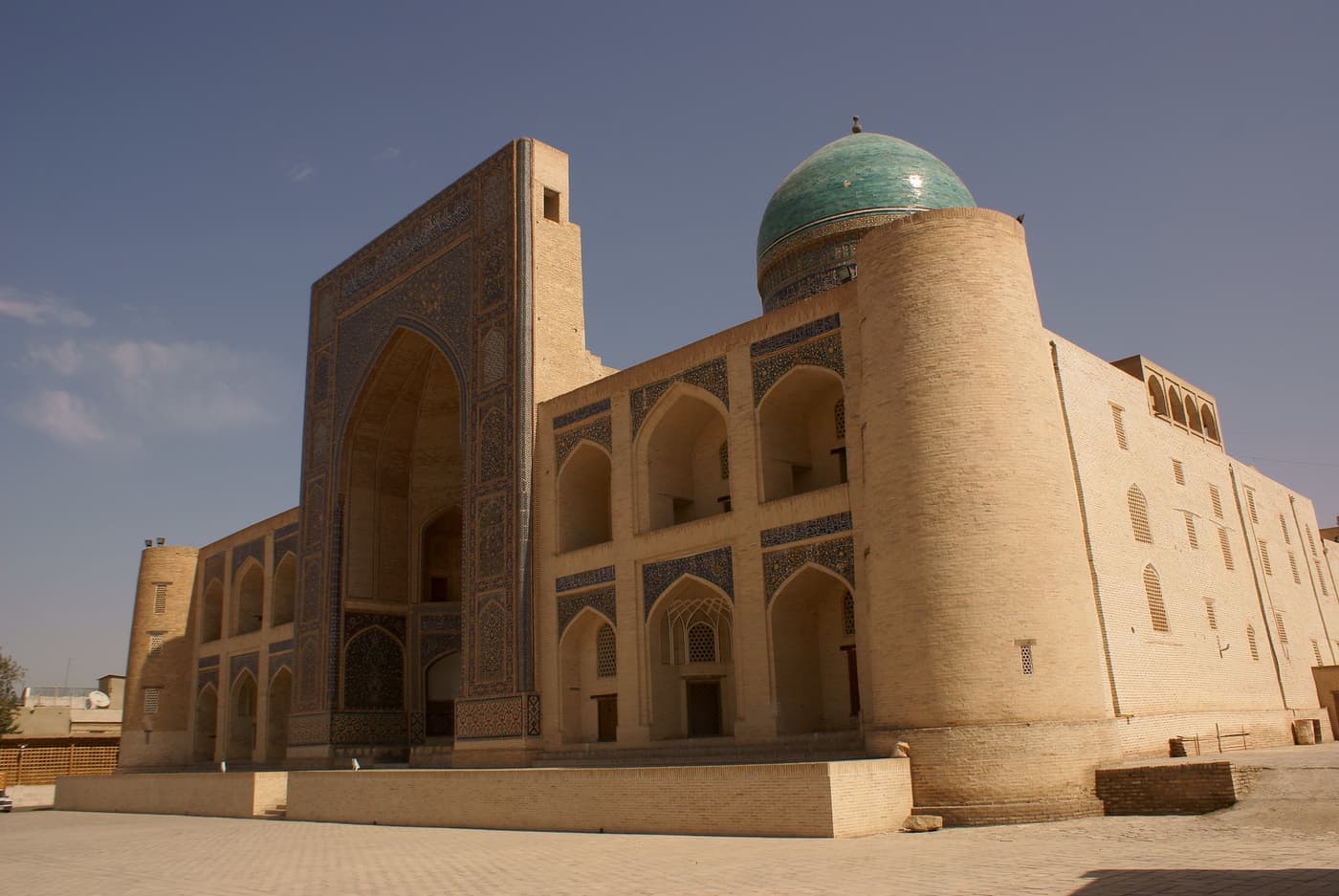 The madrasa from the side, its dome rising above the brick wall