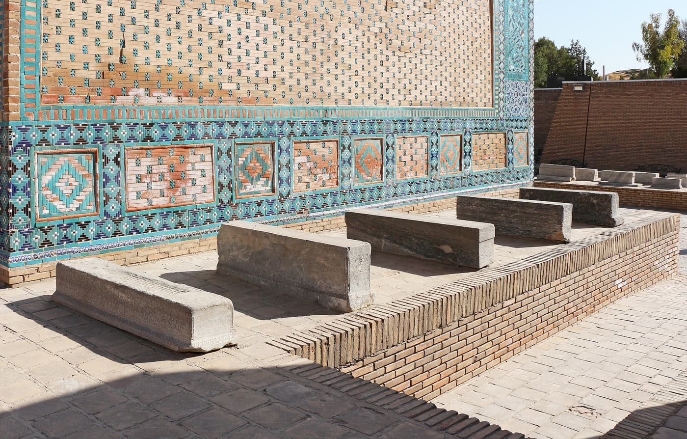 Stone tombs in front of a wall of glazed tile panels in Shah-i-Zinda